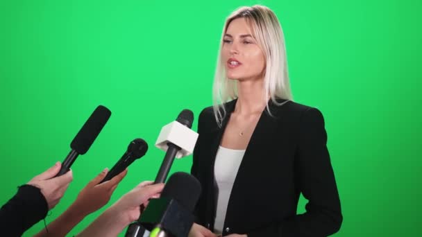 Donna caucasica rilascia un'intervista ai giornalisti, comunicazione con la stampa, microfoni nella cornice, modello cromakey. — Video Stock