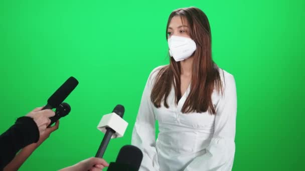 Mujer caucásica en una máscara médica da una entrevista a periodistas, comunicación con la prensa durante la pandemia del coronavirus, cromakey plantilla. — Vídeos de Stock