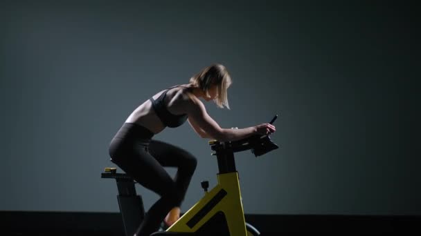 Cyklistický trénink, mladá žena se zabývá fitness na kole, provádí aerobní vytrvalostní trénink na simulátoru v tělocvičně. — Stock video