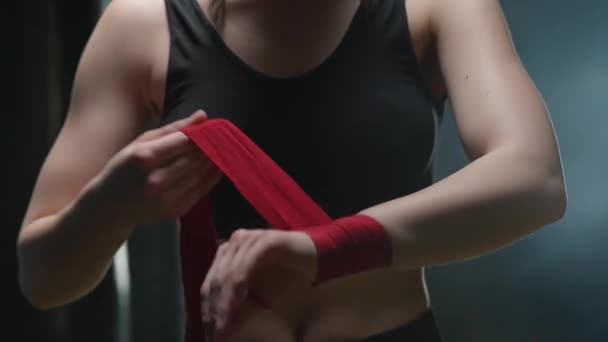 Lutadora anónima envolve as mãos com ligaduras vermelhas de boxe, dia de treino de kickboxing num ginásio. — Vídeo de Stock