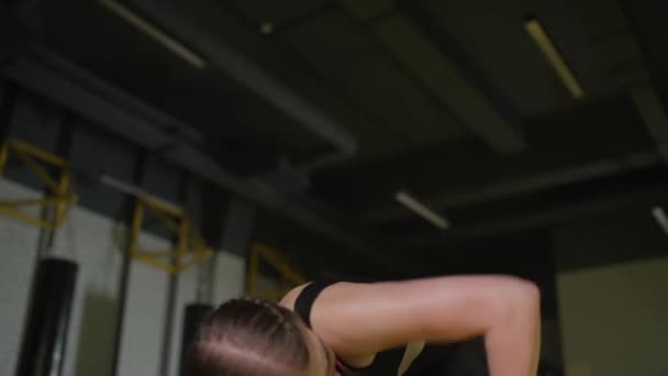 Agressieve vrouwelijke vechter traint zijn stoten, slaat een bokszak terwijl hij op de grond ligt, trainingsdag in de boksschool, kracht fit lichaam, het meisje slaat snel. — Stockvideo