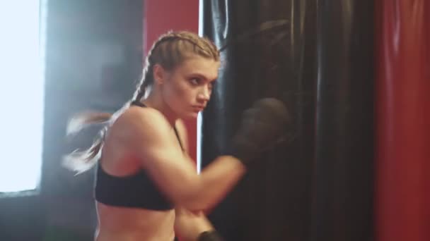 Mulher lutadora treina seus socos, treinando no ginásio de boxe, a menina treina uma série de socos rápido, vista frontal. — Vídeo de Stock