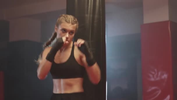 Mulher lutadora treina seus socos e defesa no ginásio de boxe, feminino treina uma série de socos, vista frontal. — Vídeo de Stock