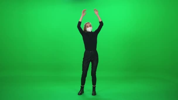 Женщина танцует на концерте, женщина в защитной медицинской маске на музыкальном концерте, танцует и хлопает в ладоши на зеленом фоне, шаблон хромаки, событие во время пандемии коронавируса. — стоковое видео