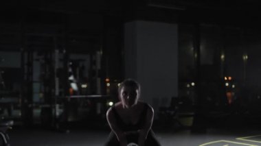 Atletik bayan kettlebell egzersizleri yapıyor, ağırlık kaldırıyor ve spor salonunda kettlebell Crossfit antrenmanı yapıyor, dramatik ışıklandırma..