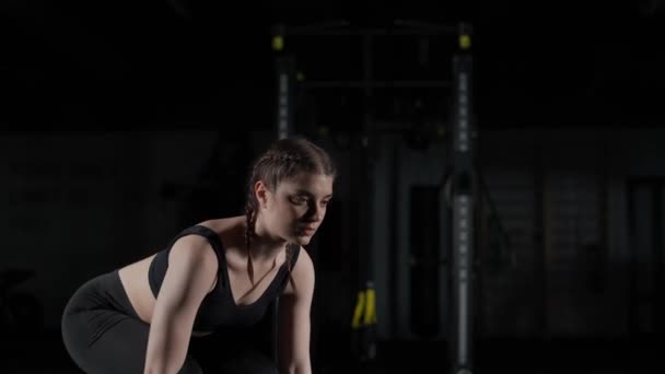 Kaukasische atletische vrouw voert oefeningen uit met lange halter, tilt lange halter en doet gewichtstraining in de sportschool, dramatisch licht. — Stockvideo