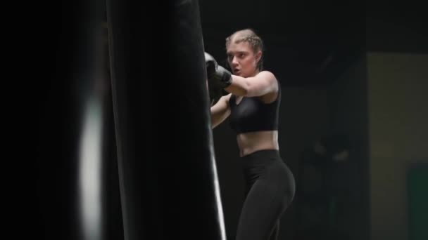 Αθλητική γυναίκα μαχητής εκπαιδεύει γροθιές του, κτυπά ένα σάκο του μποξ, kickboxing ημέρα κατάρτισης στο γυμναστήριο πυγμαχίας, 4k αργή κίνηση. — Αρχείο Βίντεο