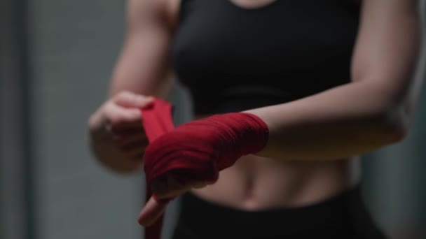 Lutadora anónima envolve as mãos com ligaduras vermelhas de boxe, dia de treino de kickboxing num ginásio, câmera lenta 4k. — Vídeo de Stock