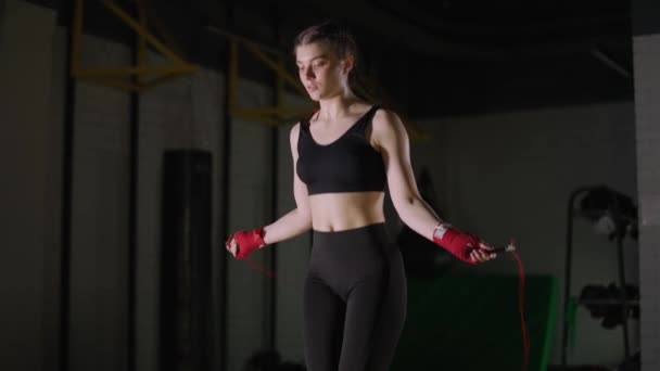 Kickboks eğitimi, atlayan bir ipe atlayan genç bir kadın boksör, formda bir vücut, 4K ağır çekim. — Stok video