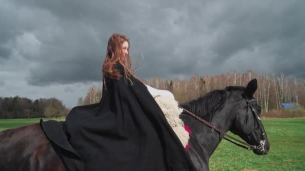 Belle femelle en robe médiévale chevauchant un cheval à travers un champ de verdure, scène médiévale, 4k slow motion. — Video