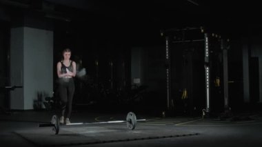 Halterci, beyaz atletik kadın halterle egzersiz yapıyor, halter kaldırıyor ve spor salonunda ağırlık çalışması yapıyor..