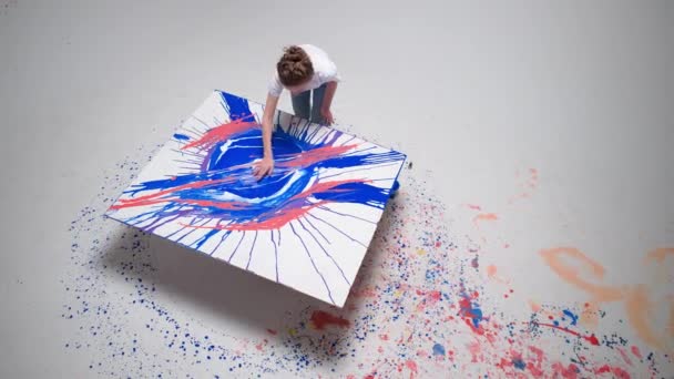 Woman artist draws with her hands on a large canvas in a white room, a talented artist draws a color blue abstraction, modern art, top view. — Video