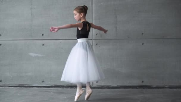 Elegantes kleines Mädchen im schwarz-weißen Tutu-Kleid, Ballett tanzen und choreografische Elemente auf grauem Hintergrund aufführen, Probe. — Stockvideo