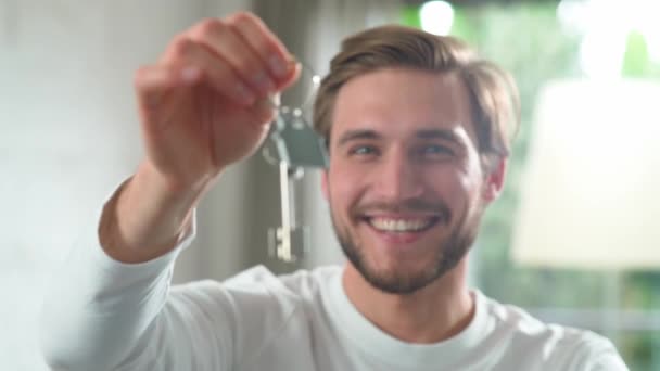 Подорожній, щасливий чоловік у новій квартирі, чоловік посміхається і показує ключі від нової квартири до камери, позитивні емоції, повільний рух 4k . — стокове відео