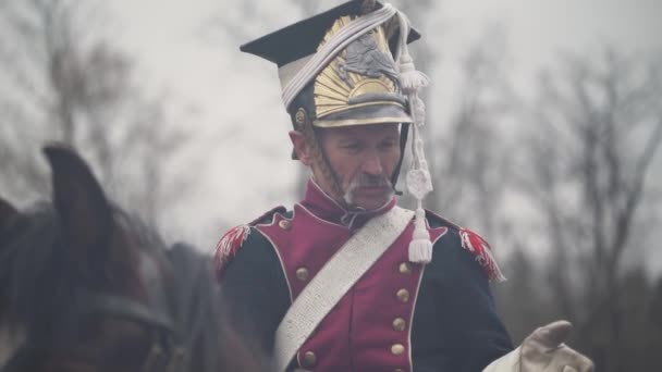 Porträtt av en vuxen manlig husar i medeltida dräkt, soldat på hästryggen, samtal med en medsoldat på slagfältet, slaget vid Napoleon, närbild. — Stockvideo