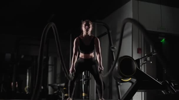 Atletisk kvinna utför övningar med stridsrep, uthållighetsträning i gymmet, 4k slow motion. — Stockvideo