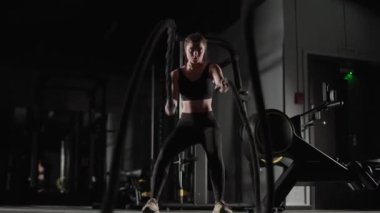 El bilgisayarı, atletik kadın dövüş halatlarıyla egzersiz yapıyor, spor salonunda dayanıklılık eğitimi alıyor, 4K ağır çekim..