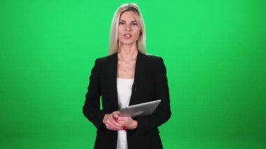 Takım elbiseli kadın muhabir kameraya bakar ve mikrofonla konuşur, elinde tablet, yeşil arka planda bir kadın, TV haber ajansları için şablon, iş yerinde gazeteci.