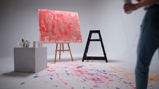Slow motion, vrouwelijke kunstenaar tekent met een borstel op een groot doek in een witte kamer, een getalenteerde kunstenaar tekent een kleur rode abstractie, moderne kunst in olieverf. — Stockvideo