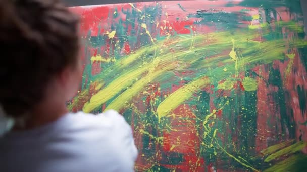 Baksidan, kvinnliga konstnären ritar med spray, färg på en stor duk i ett vitt rum, en begåvad konstnär ritar en färg abstraktion, 4k slow motion. — Stockvideo