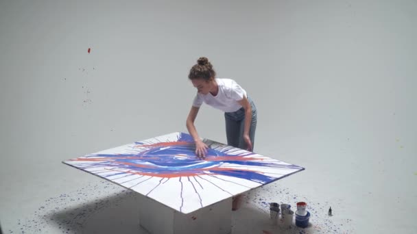 Artiste féminine dessine avec ses mains sur une grande toile dans une pièce blanche, une artiste talentueuse dessine une abstraction de couleur bleue, art moderne, vue de dessus. — Video