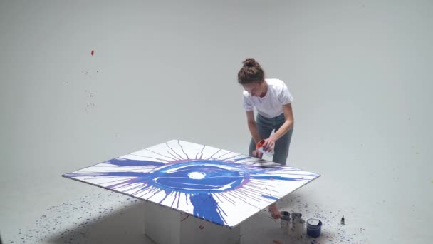 Fiatal női művész rajzol a kezét egy nagy vászon egy fehér szobában, egy tehetséges művész rajzol egy színes kék absztrakció, modern művészet, felső nézet. — Stock videók