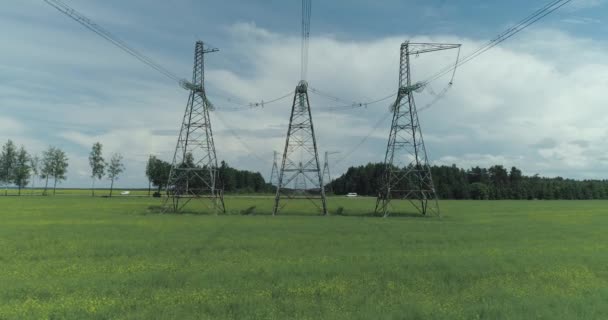 Trasporto di energia elettrica, linea elettrica vicino all'autostrada, vista industriale sulla linea di trasmissione elettrica in campo colza, torri in acciaio con fili e comunicazione di alimentazione elettrica — Video Stock