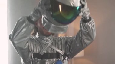 Astronot kıyafeti giymiş neşeli bir adam oturma odasında durur, bir astronot miğfer takar, bir uzay adamı oynar..