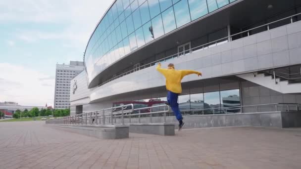 자유롭게 달리고 있는 젊은이는 도시 의장 애물을 뛰어넘으며 현대 건물 근처에서 훈련받는 분야에서 동전을 던진다 4k 느린 동작. — 비디오