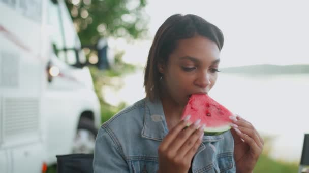 一个快乐的非洲女性在自然界中的画像，一个年轻的女人吃西瓜，吃水果，夏天，在自然界中野餐，4k慢动作. — 图库视频影像