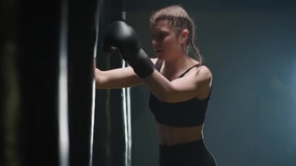 Επιθετική γυναίκα μαχητής εκπαιδεύει γροθιές του, κτυπά ένα σάκο του μποξ, ημέρα κατάρτισης στο γυμναστήριο πυγμαχίας, δύναμη ταιριάζει σώμα. — Αρχείο Βίντεο
