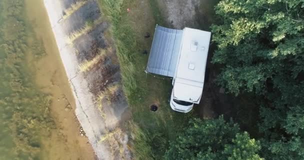 Recreación al aire libre, vista desde una altura de una casa móvil de pie cerca de un lago en el bosque, descansar en un coche de camping durante el auto-aislamiento, vista aérea. — Vídeos de Stock