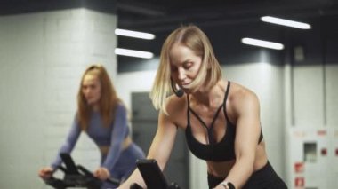 Sağlık, bisiklet süren kadınlar, spor salonundaki simülatörlere aerobik dayanıklılık eğitimi veren iki kadın, bisiklet eğitimi....