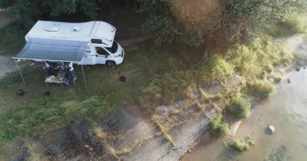 Été, groupe de jeunes profitent d'une fête dans la nature près du lac, les gens communiquent et se détendre dans la nature près du camping-car, coucher de soleil, vue de la hauteur. — Video