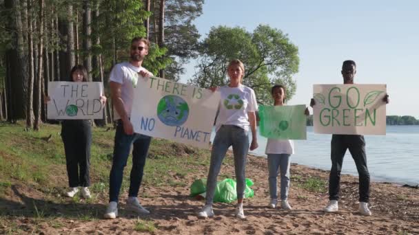 Luchadores ecologistas con afiches en sus manos protestan contra la contaminación de la naturaleza, una reunión de voluntarios de diferentes razas y edades, la gente sostiene un afiche con llamados a salvar la naturaleza, no — Vídeo de stock