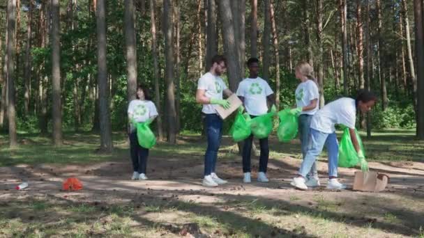 Eco-activistas y voluntarios limpian basura en el bosque, luchan contra la contaminación plástica de la naturaleza, personas de diferentes razas y edades limpian basura en el bosque, cuidan de la naturaleza. — Vídeos de Stock
