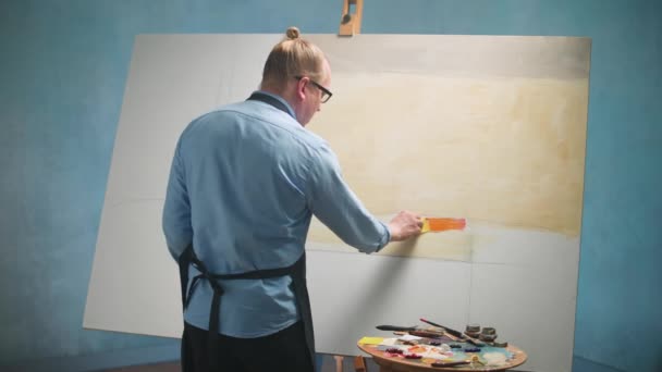 Vista posterior de la persona creativa en el trabajo, un talentoso artista masculino dibuja un cuadro abstracto en un lienzo grande, 4k cámara lenta. — Vídeos de Stock
