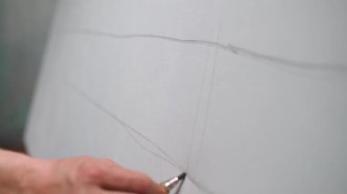 Çalışan yaratıcı bir adam, yetenekli bir sanatçı tuval üzerinde çizimler yapıyor, çizgiler çiziyor, 4k ağır çekim..