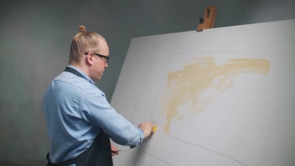 Zpomalený, kreativní člověk v práci, talentovaný dospělý umělec zakrývá plátno béžovou olejomalbou, základní nátěrem a kreslí pozadí. — Stock video