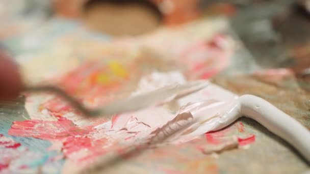 Un artista mescola pittura ad olio con un coltello palette, una persona creativa al lavoro, primo piano, 4k rallentatore. — Video Stock