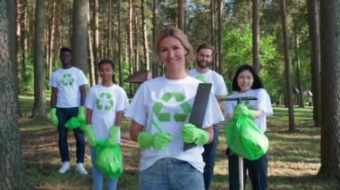 Çevre aktivistleri doğanın korunması için savaşıyor, aktivistler ayakta duruyor ve kameraya bakıyor, beyaz kadın ön planda duruyor, insanlar çöpleri temizliyor ve temizliyor.