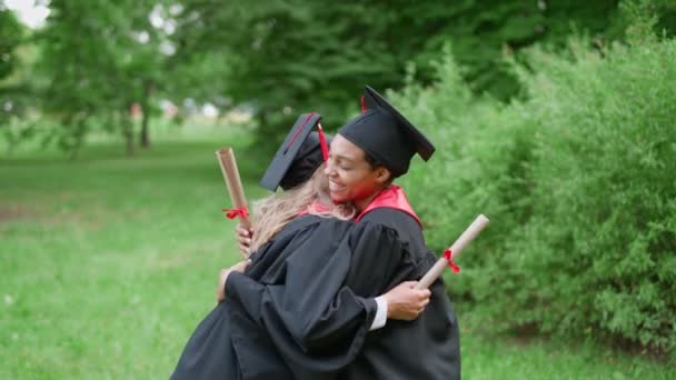 Internationale Universitätsabsolventinnen feiern, glückliche Absolventinnen in Roben umarmen sich und gratulieren sich zum Abschluss, ein emotionaler Moment, 4k Zeitlupe. — Stockvideo