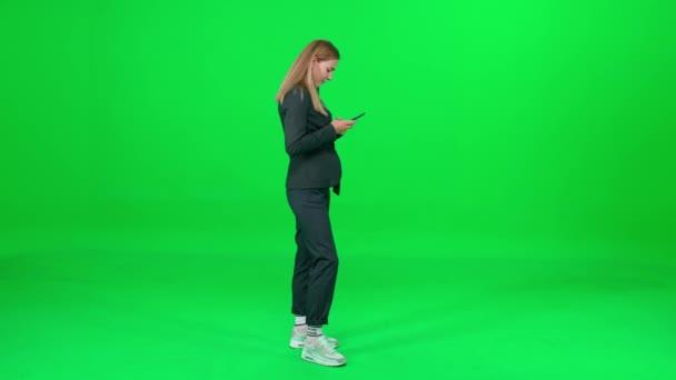 Üzletasszony öltönyben áll a chroma kulcs háttér, nő használ okostelefon, SMS-ezés és szörfözés az interneten, zöld háttér, chromakey sablon. — Stock videók