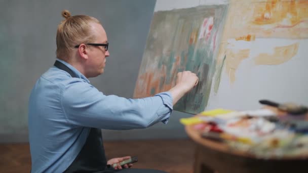 Kreative Person bei der Arbeit, ein talentierter erwachsener Mann Künstler bedeckt die Leinwand mit Ölfarbe, zeichnet das moderne abstrakte Bild, Künstler-Werkstatt, 4k Zeitlupe. — Stockvideo
