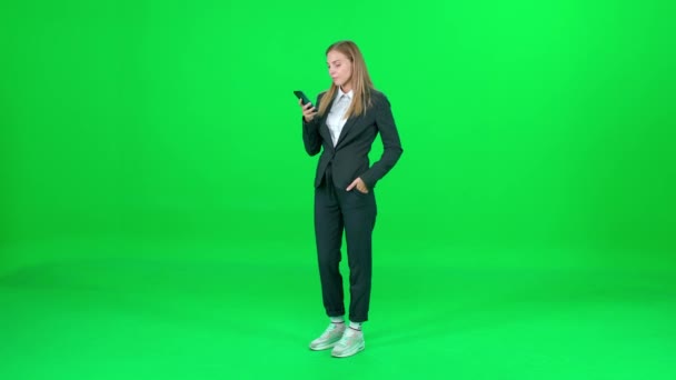 Üzletasszony öltönyben áll a chroma kulcs háttér, nő használ okostelefon és beszél a mobiltelefon, zöld háttér, chromakey sablon. — Stock videók