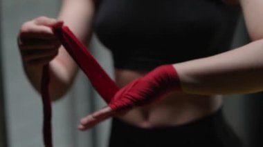 İsimsiz kadın boksör ellerini kırmızı boks bandajlarıyla sarar. Spor salonunda kickboks antrenmanı yapar..