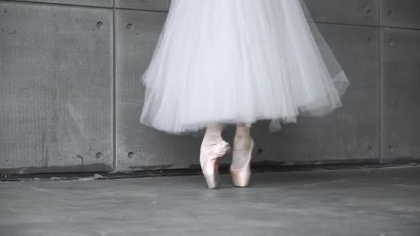 Handheld, Feminino elegante em um tutu branco, balé de dança e equilíbrio em sapatos Pointe, vista das pernas, fundo cinza, ensaio. — Vídeo de Stock