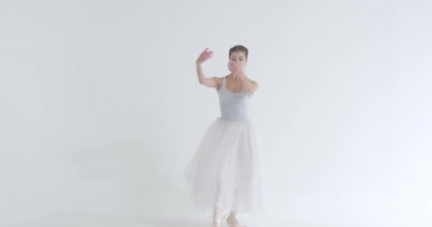 Femme élégante dans un tutu blanc, danse ballet et exécuter des éléments chorégraphiques sur un fond blanc, répétition. — Video