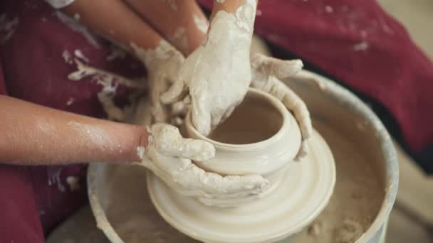 Gezamenlijk werk, productie van handgemaakt servies, het jonge paar pottenbakker maakt een kruik van klei, bovenaanzicht van de handen, handwerk. — Stockvideo