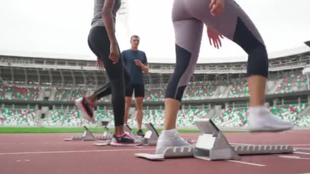 Mulher sprinters estão treinando no estádio, duas mulheres esportivas estão competindo em corrida de curta distância, o treinador controla o tempo. — Vídeo de Stock